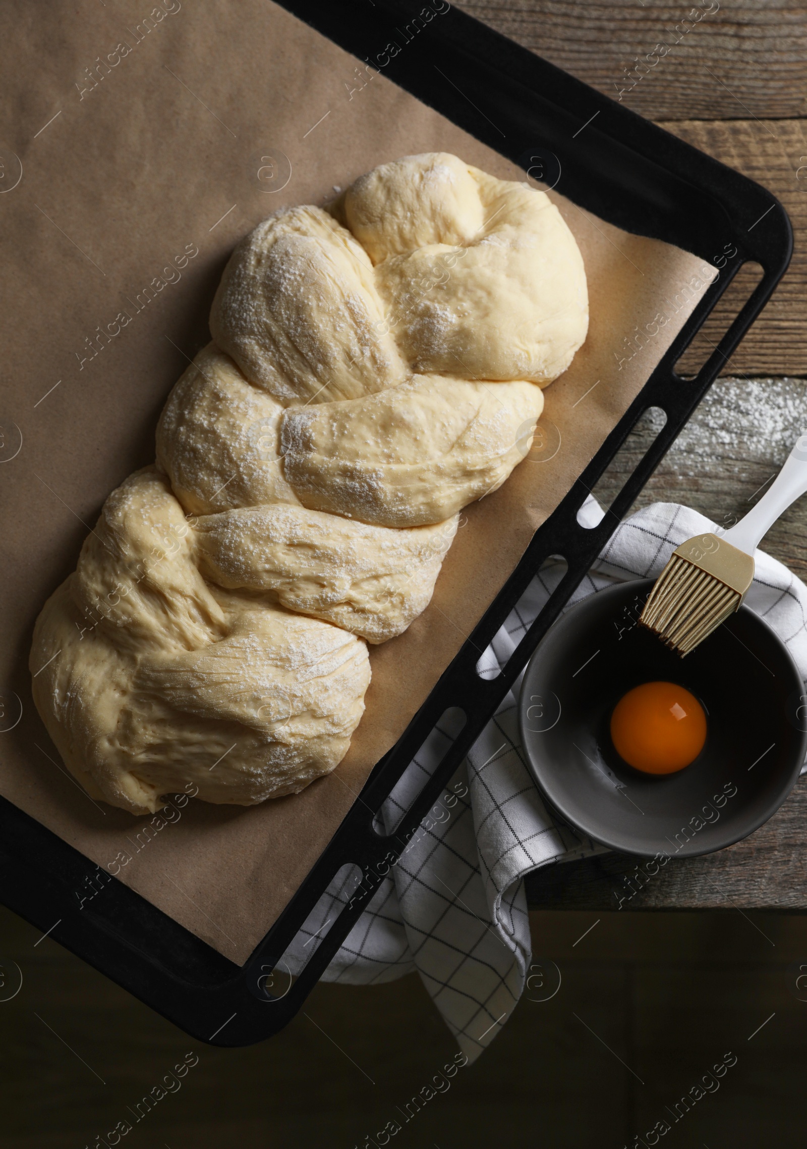 Photo of Homemade braided bread and ingredients on wooden table, flat lay. Cooking traditional Shabbat challah