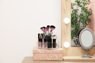 Photo of Organizer with cosmetic products for makeup on table near mirror. Space for text