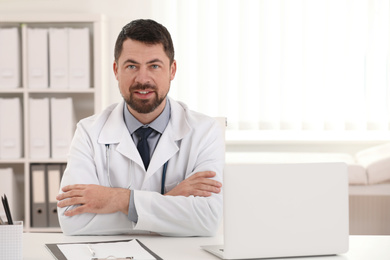 Portrait of male doctor in white coat at workplace