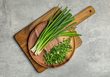 Chopped green spring onion and stems on grey table, top view