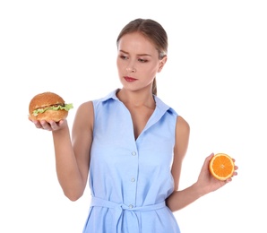 Slim woman with burger and orange on white background. Healthy diet