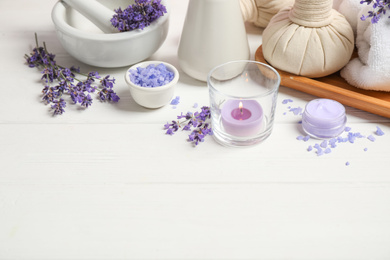 Cosmetic products and lavender flowers on white wooden table. Space for text
