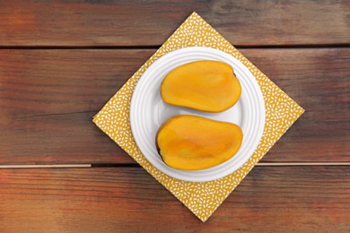 Photo of Delicious cut ripe mangos on wooden table, top view