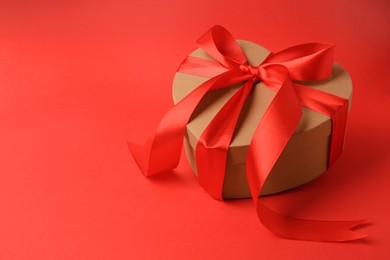 Beautiful heart shaped gift box with bow on red background, space for text
