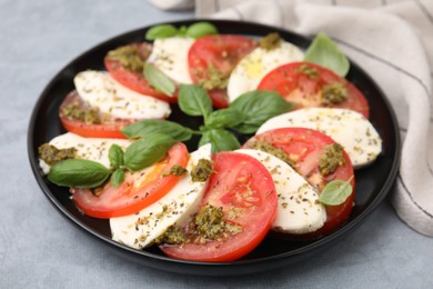 Photo of Plate of delicious Caprese salad with pesto sauce on grey table, closeup