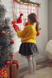Little girl taking gift from New Year advent calendar at home