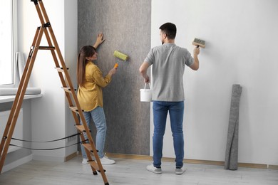 Photo of Woman and man hanging wallpaper in room