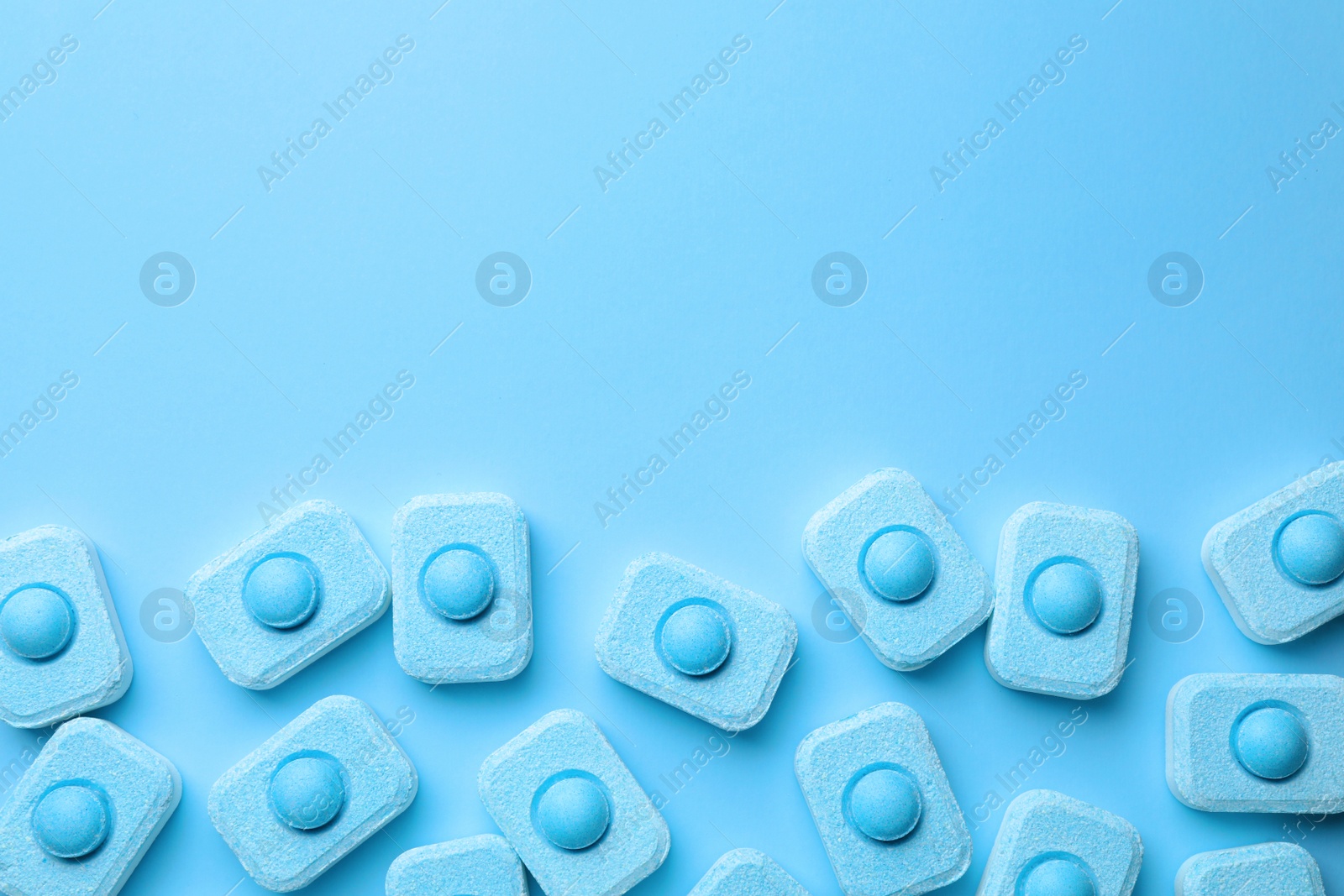Photo of Water softener tablets on light blue background, flat lay. Space for text