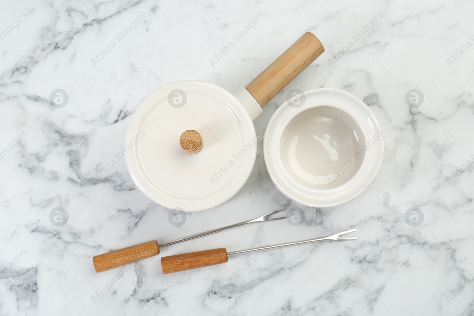 Photo of Fondue set on white marble table, flat lay