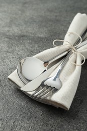 Stylish silver cutlery and napkin on grey table