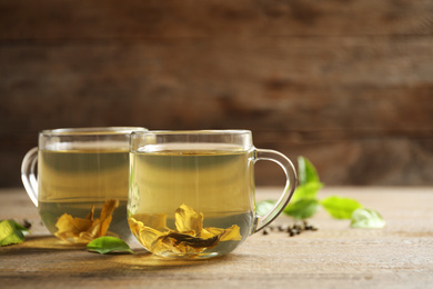 Photo of Cups of green tea and leaves on wooden table