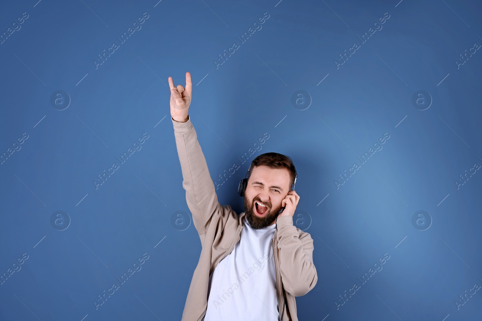 Photo of Portrait of handsome bearded man listening to music on color background