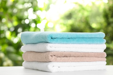 Stack of clean soft towels on table against blurred background
