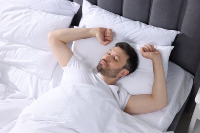 Photo of Handsome man sleeping in soft bed, above view