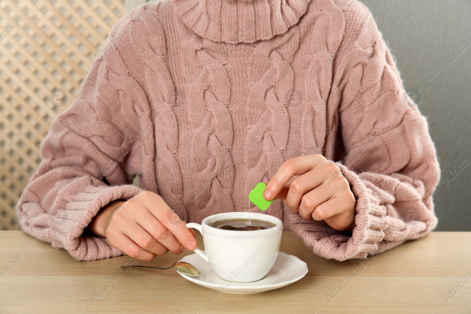 Photo of Woman with cup of tea at wooden table, closeup