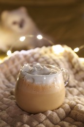 Glass cup of delicious hot cocoa on light blanket