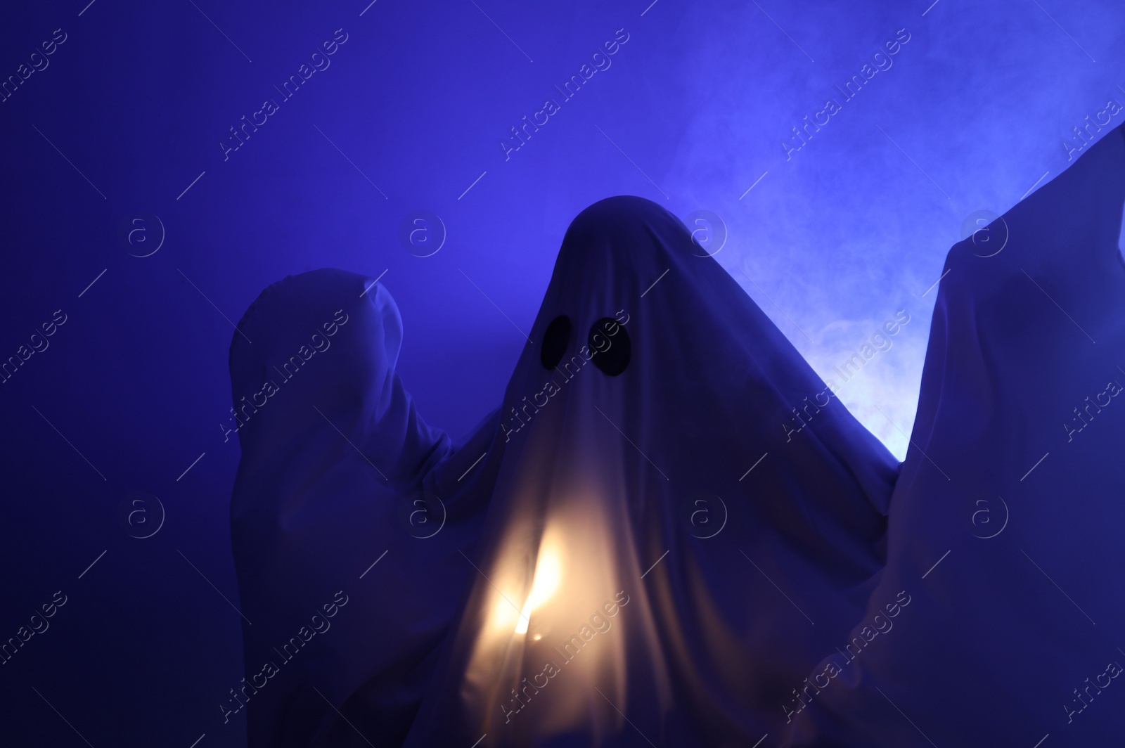 Photo of Creepy ghost. Woman covered with sheet in blue light