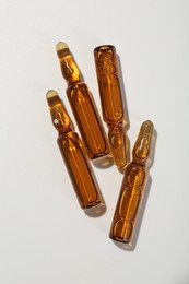 Glass ampoules with liquid on white background, top view