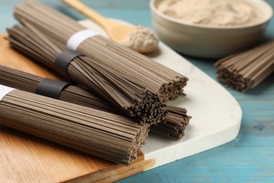 Photo of Uncooked buckwheat noodles (soba) on light blue wooden table, closeup