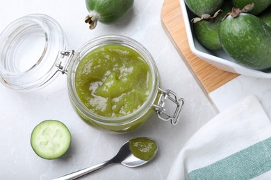 Photo of Feijoa jam and fresh fruits on light grey table, flat lay