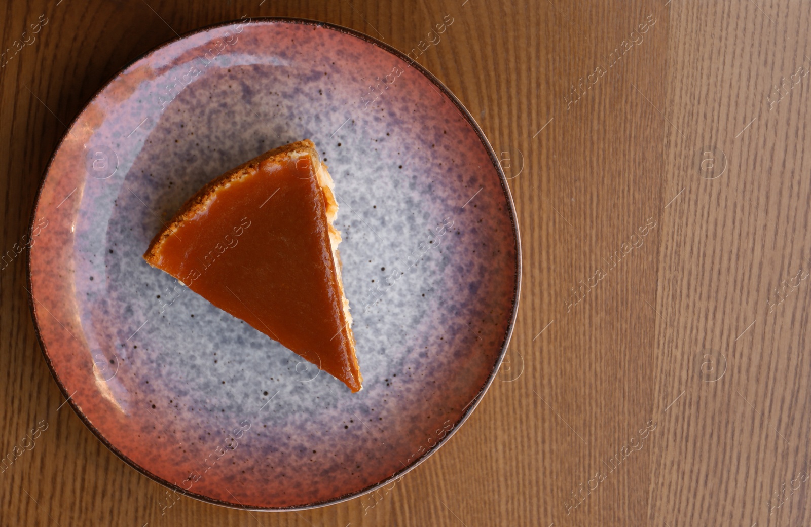 Photo of Plate with slice of cake on wooden table, top view