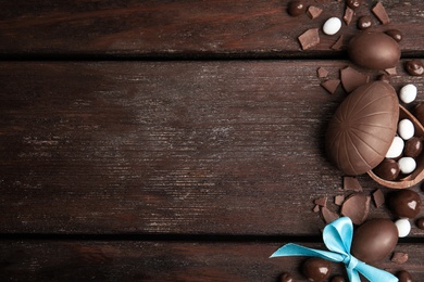 Photo of Flat lay composition with delicious chocolate Easter eggs and candies on wooden table. Space for text