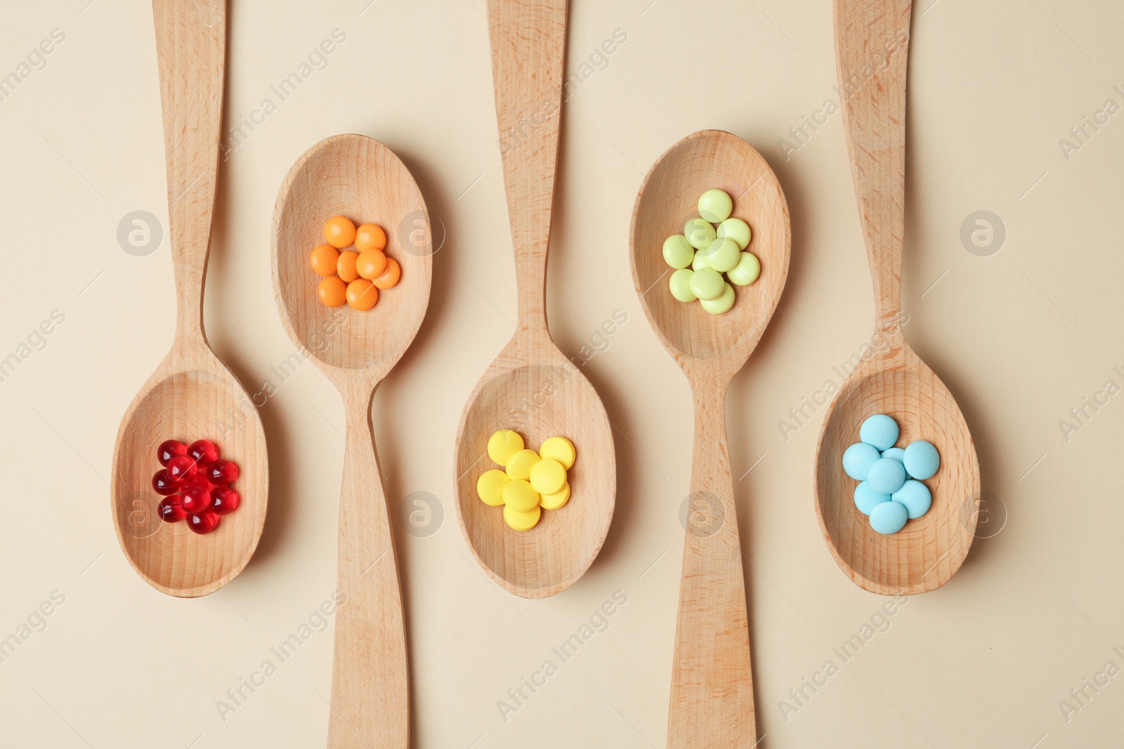 Photo of Wooden spoons with different pills on color background, top view