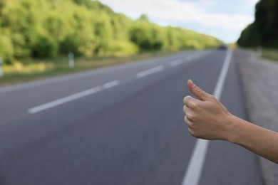 Photo of Woman catching car on road, closeup. Hitchhiking trip