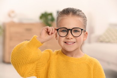 Photo of Portrait of cute little girl wearing glasses indoors