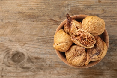 Bowl of dried figs on wooden table, top view. Space for text