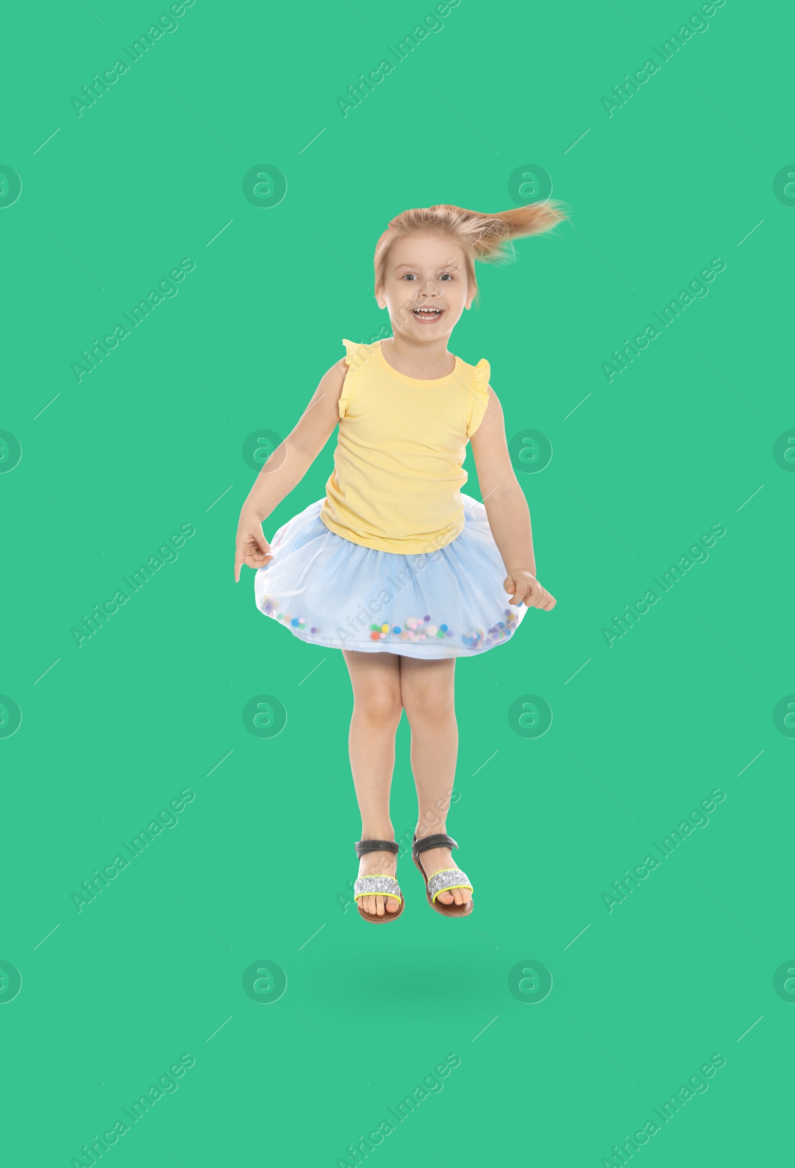 Image of Happy cute girl jumping on turquoise background