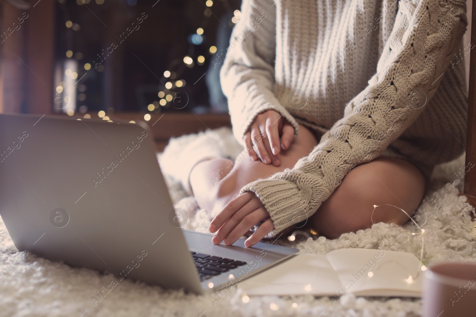 Photo of Woman using laptop at home in winter evening, closeup