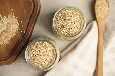 Photo of Jars and spoon with white quinoa on light grey table, flat lay