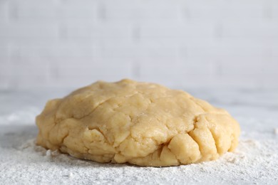 Photo of Making shortcrust pastry. Raw dough and flour on table