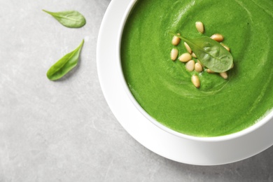 Photo of Bowl with fresh green healthy spinach soup on grey table, top view. Space for text