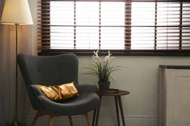 Photo of Stylish living room interior with comfortable armchair and window blinds