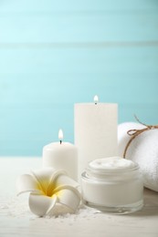 Photo of Composition with cream and burning candles on white wooden table. Spa treatment
