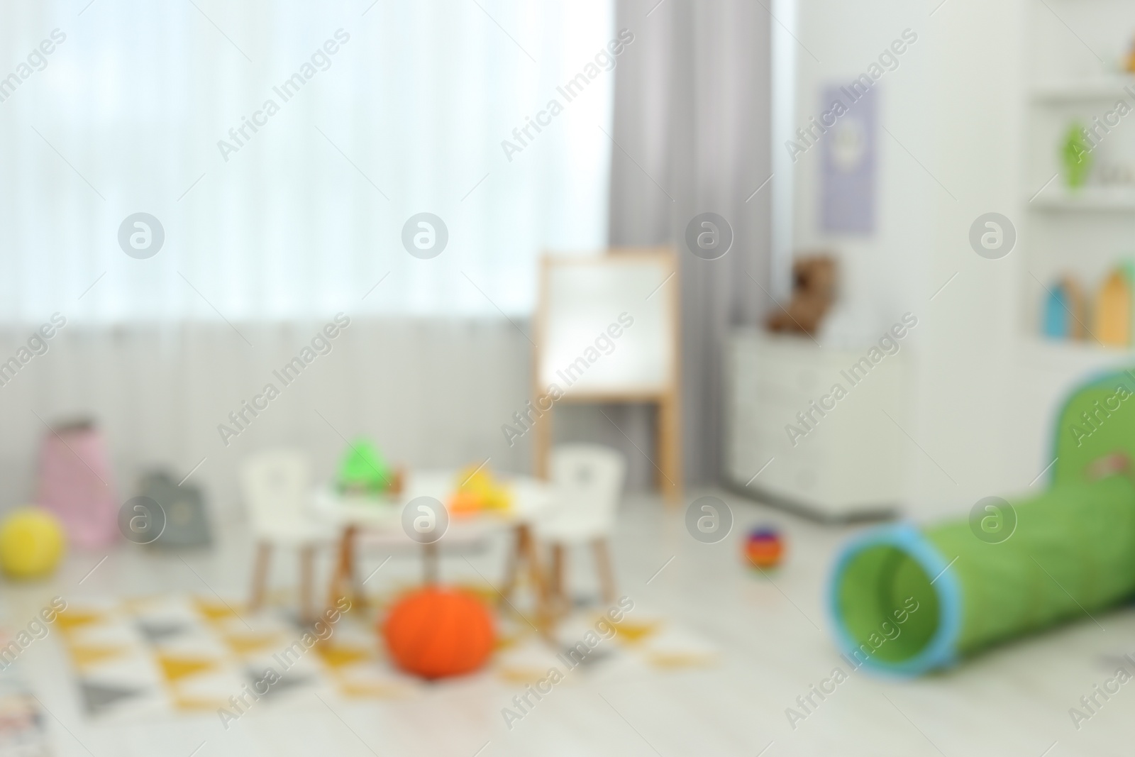 Photo of Blurred view of child`s playroom with different toys and furniture. Stylish kindergarten interior