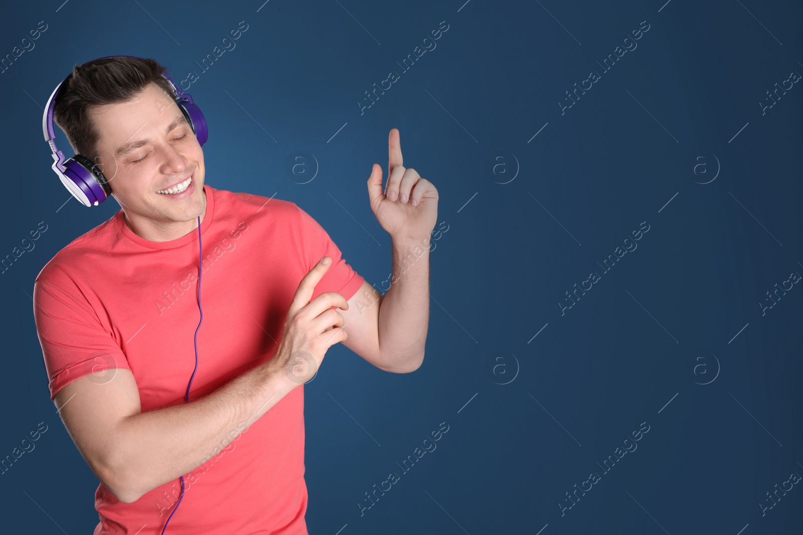 Photo of Man enjoying music in headphones on color background. Space for text