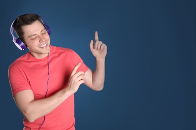 Photo of Man enjoying music in headphones on color background. Space for text