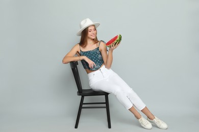 Photo of Beautiful girl on chair with watermelon against grey background