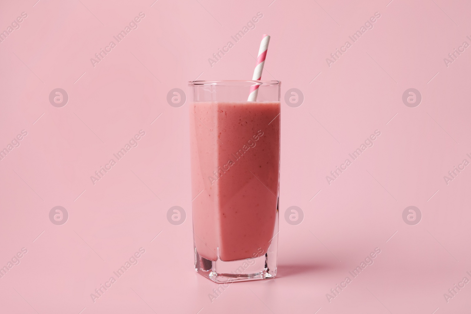 Photo of Glass with delicious berry smoothie on pink background