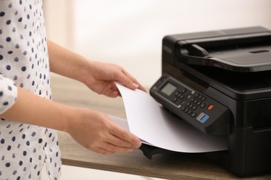 Photo of Employee using modern printer in office, closeup