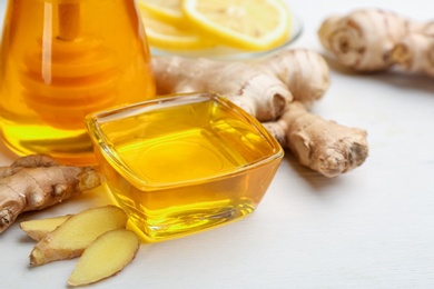 Photo of Ginger and honey on white table, closeup. Natural cold remedies