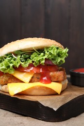 Photo of Delicious burger with tofu, fresh vegetables and sauce on wooden table