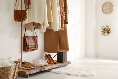 Photo of Rack with stylish shoes and women's clothes in dressing room. Modern interior design