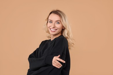 Happy woman in stylish warm sweater on beige background