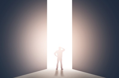 Image of Silhouette of man standing in front of light hole, back view