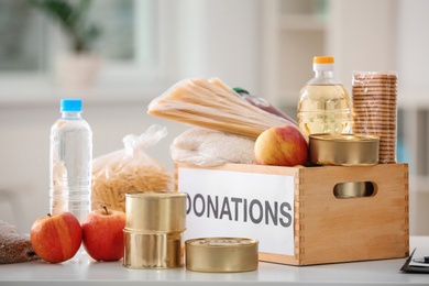 Donation box with food products on table indoors