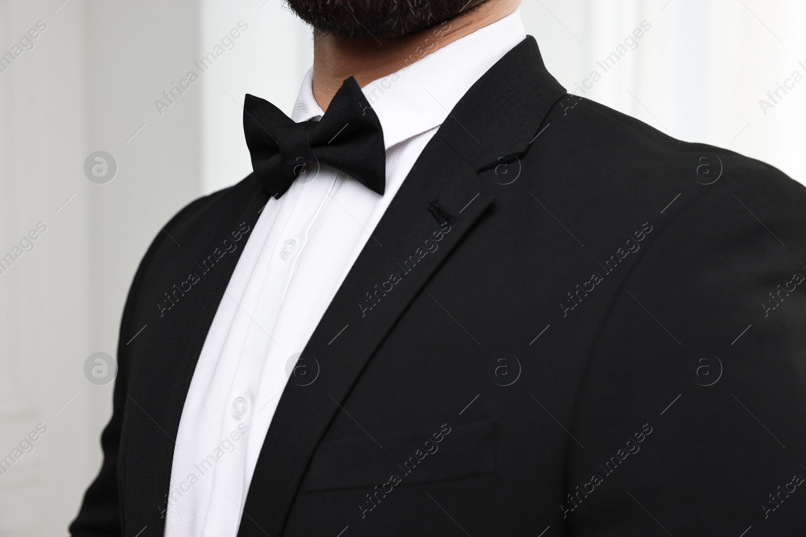 Photo of Man in suit, shirt and bow tie indoors, closeup